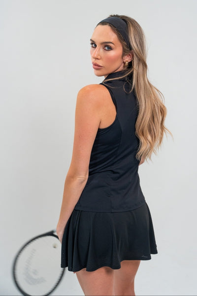 Woman in a black tennis outfit holding a racket against a white background
